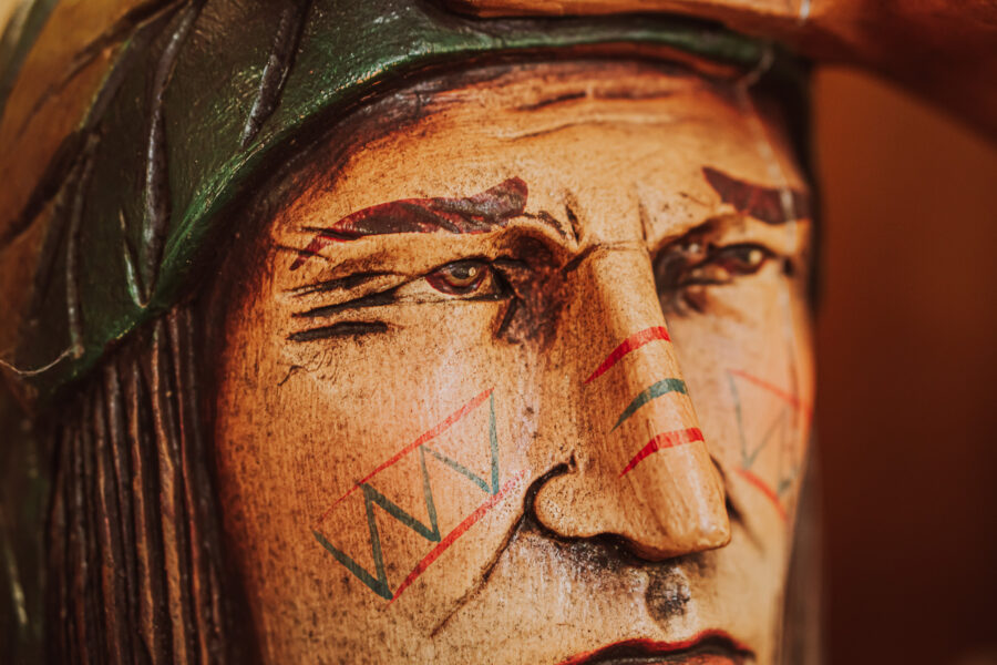 Detailed close-up of hand-painted Native American wood carving with face paint at Castle Antiques Haliburton Ontario.