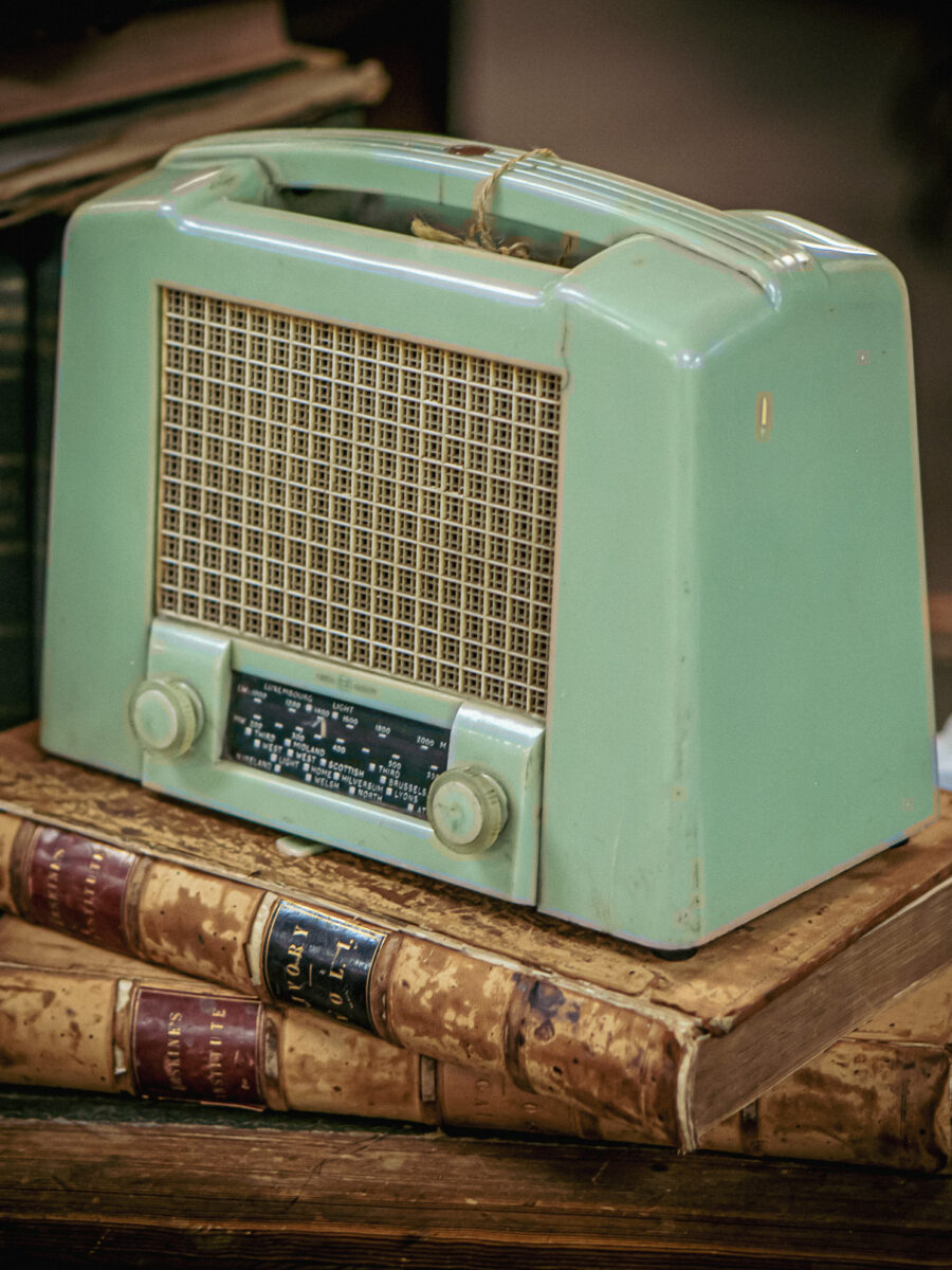 Retro portable radio in pastel green sitting on antique books at Castle Antiques Haliburton Ontario.