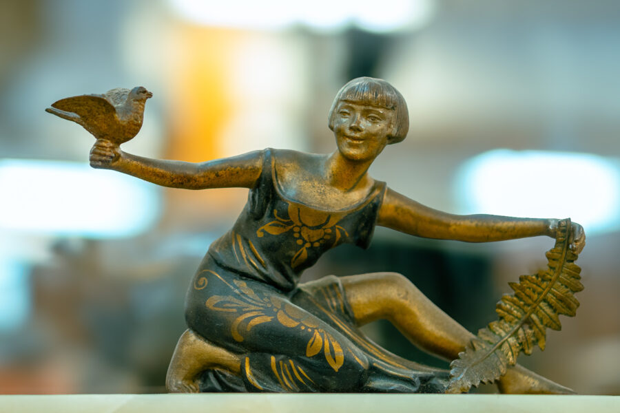 Bronze art deco figurine of a woman holding a bird and palm frond at Castle Antiques Haliburton Ontario.