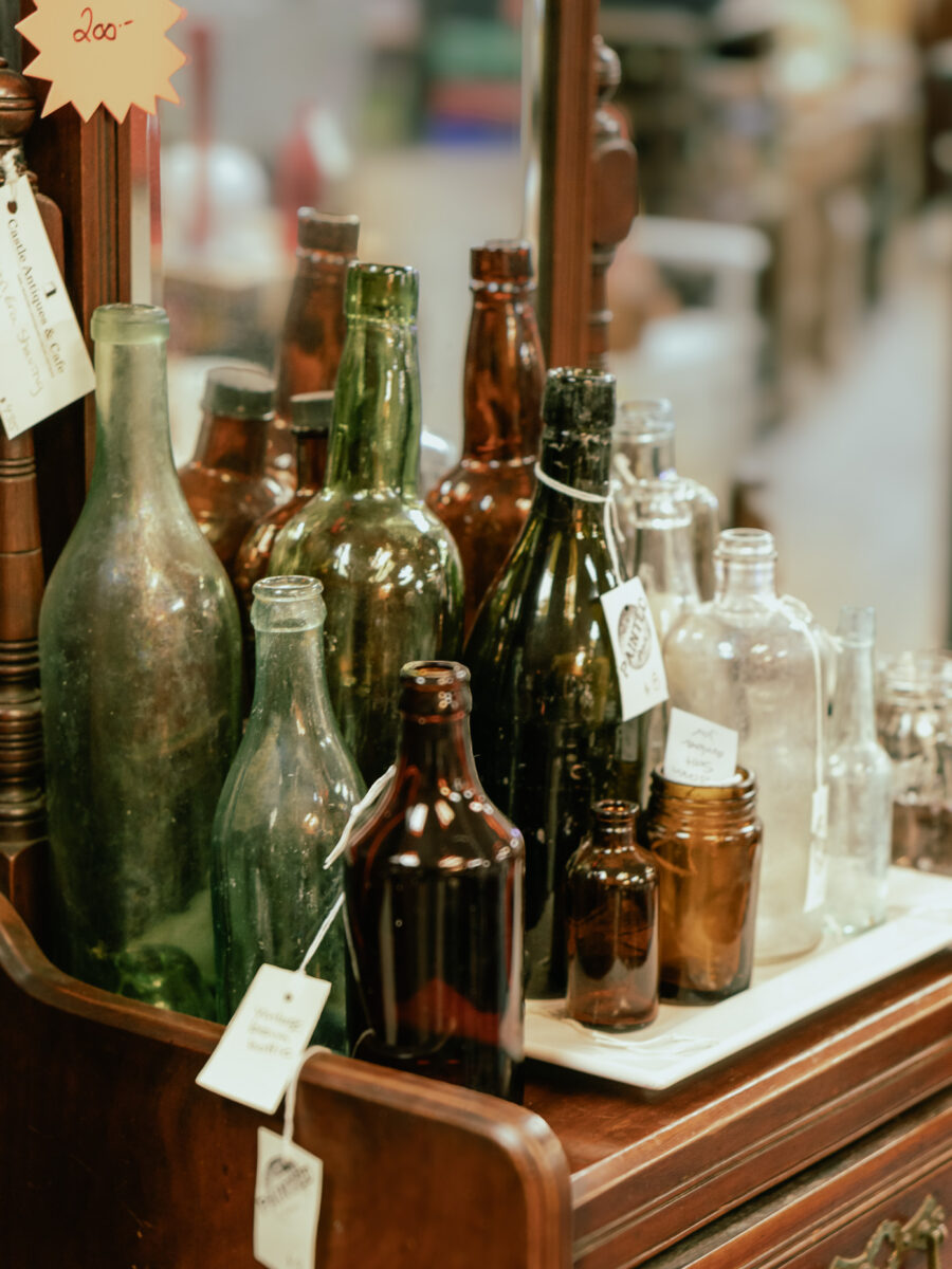 Assorted vintage green, brown, and clear glass bottles on display at Castle Antiques Haliburton Ontario.