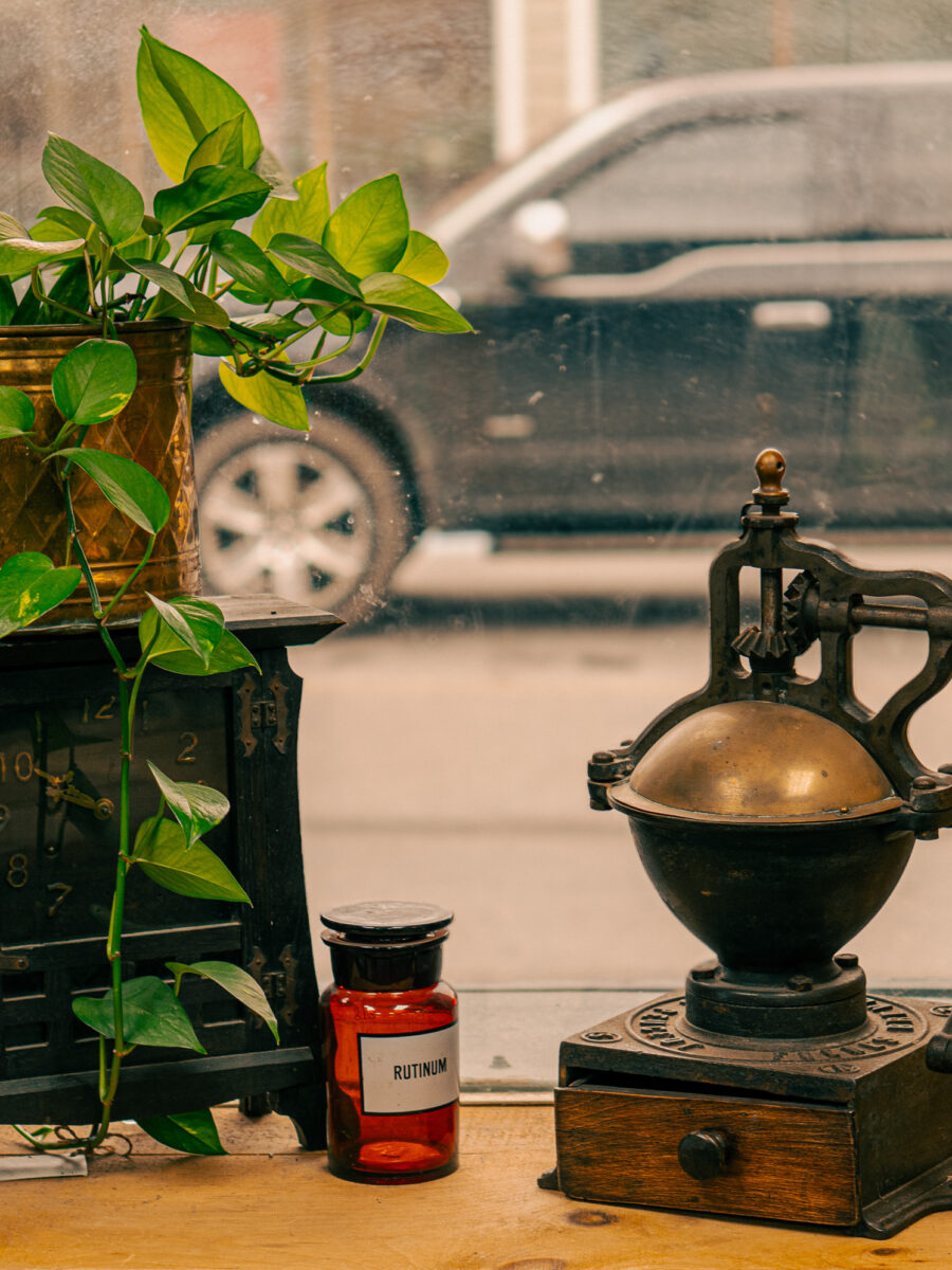 Rustic cast iron coffee grinder with old wooden clock and red apothecary jar at Castle Antiques Haliburton Ontario.