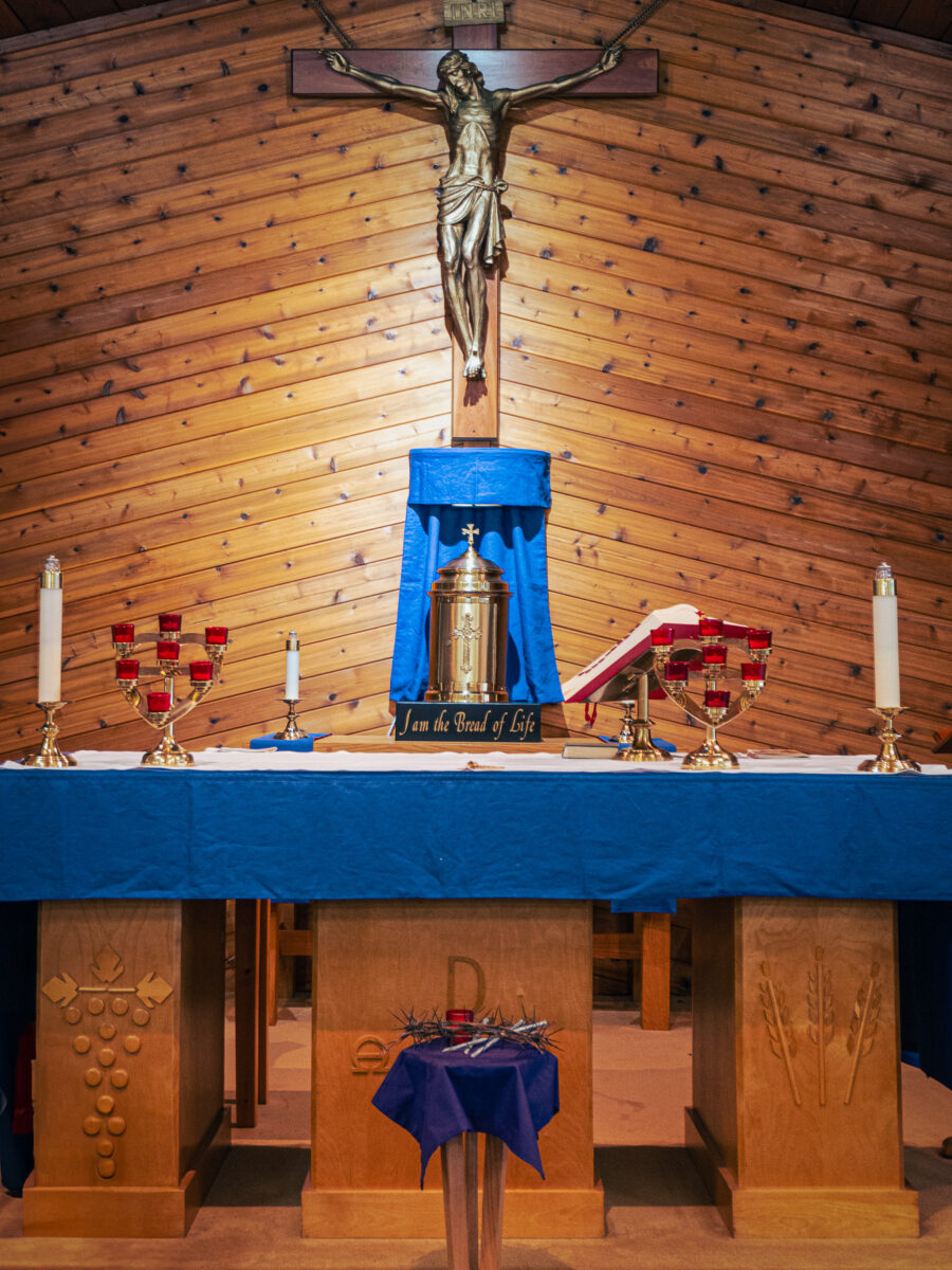 ChatGPT said: Catholic church altar with blue cloth, gold tabernacle, crucifix, and liturgical candles, Minden Ontario