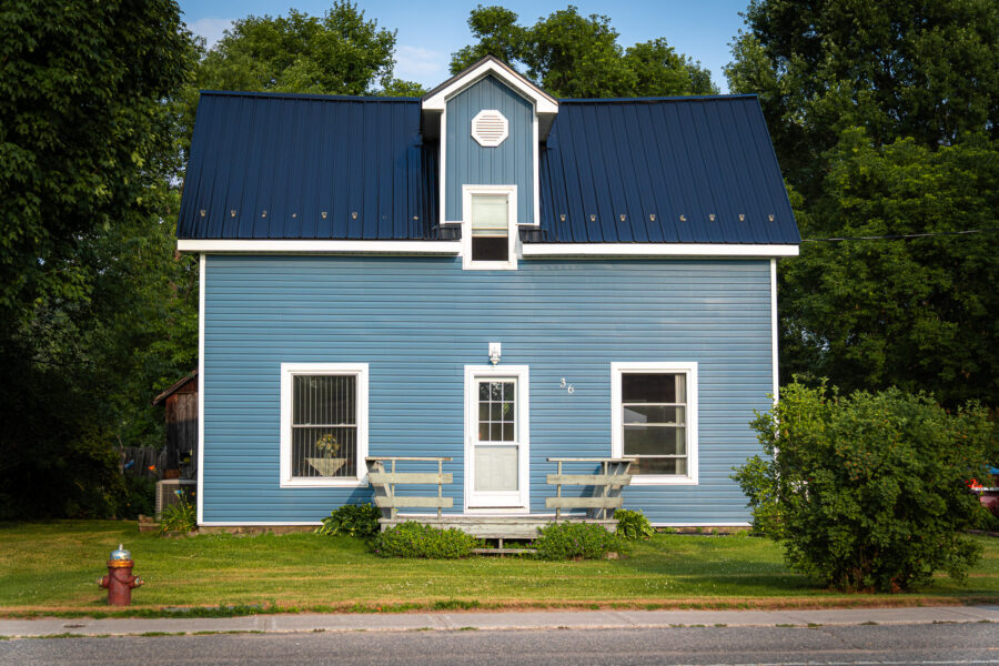 Blue house with white trim and metal roof on a quiet street, Minden Ontario