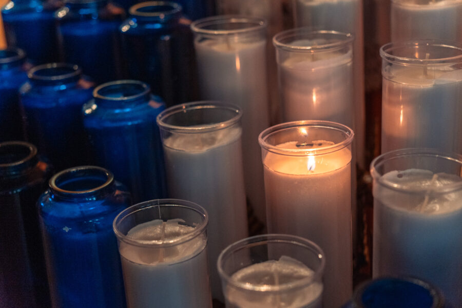 Lit votive candles surrounded by blue glass holders inside Our Lady of Fatima Church, Minden, Ontario.