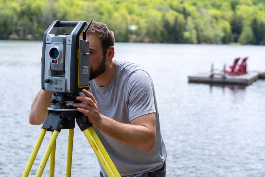 Inspire Contracting’s Tyler Hall using Trimbo surveying equipment to measure elevations for a cottage construction project