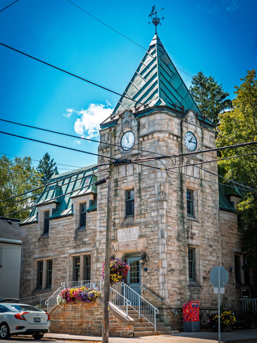 Historic Westport Ontario post office clock tower with green roof and flower planters