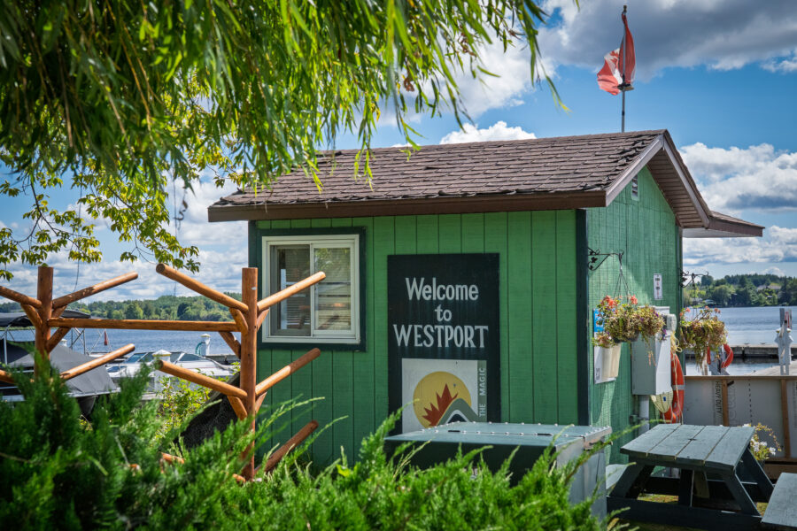 Welcome to Westport Ontario sign at marina with lake view and picnic tables